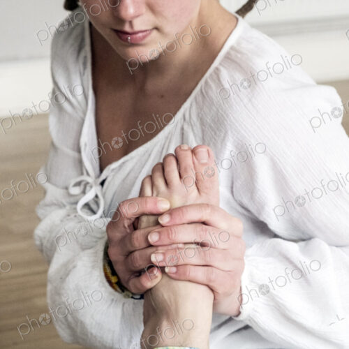 Young woman wearing headscarf and white blouse sitting on floor in yoga pose.