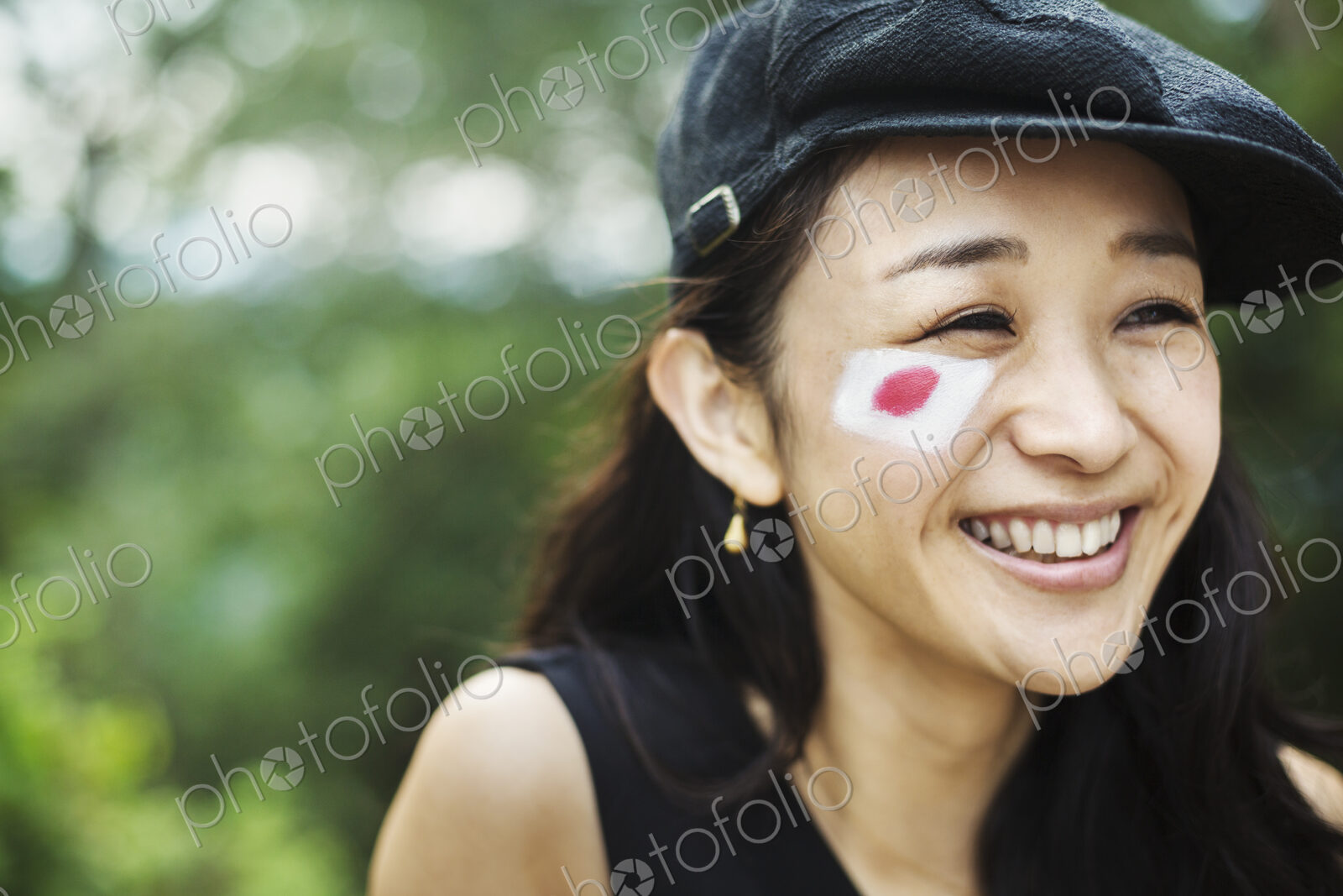 Young woman with black hair wearing flat cap, Japanese flag painted on her cheek.