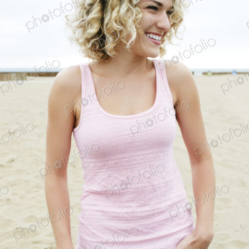 Young woman with blond curly hair standing on sandy beach. Young woman with blond curly hair standing on sandy beach.