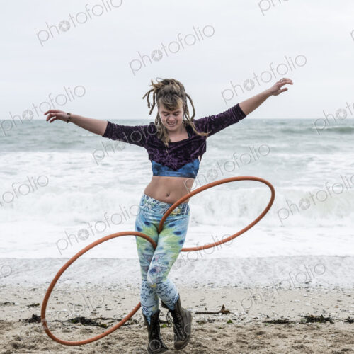Young woman with brown hair and dreadlocks standing on a sandy beach by the ocean,… Young woman with brown hair and dreadlocks standing on a sandy beach by the ocean,…