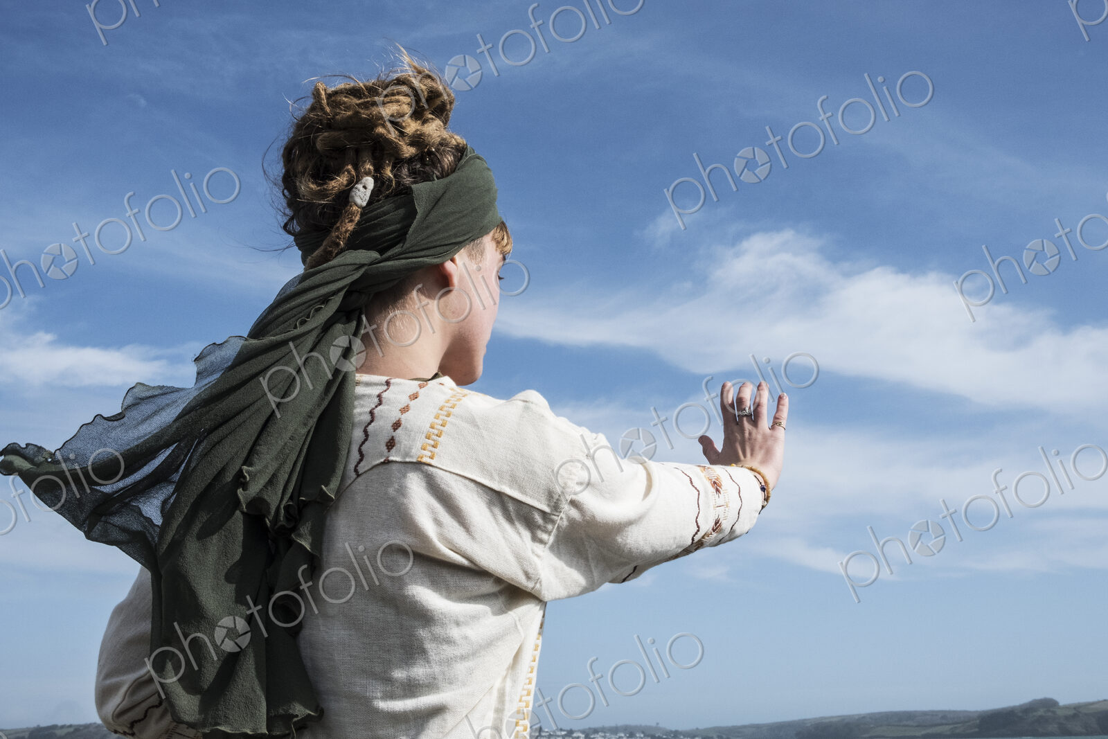 Young woman with brown hair and dreadlocks wearing headscarf standing on a beach,…