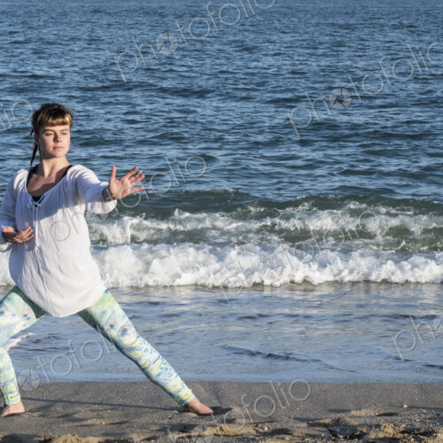 Young woman with brown hair wearing white blouse standing on a beach by the ocean,… Young woman with brown hair wearing white blouse standing on a beach by the ocean,…