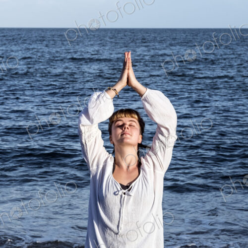 Young woman with brown hair wearing white blouse standing on a beach by the ocean,… Young woman with brown hair wearing white blouse standing on a beach by the ocean,…