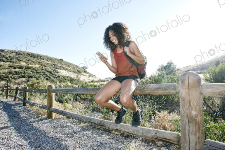 Young woman with curly brown hair hiking in urban park.
