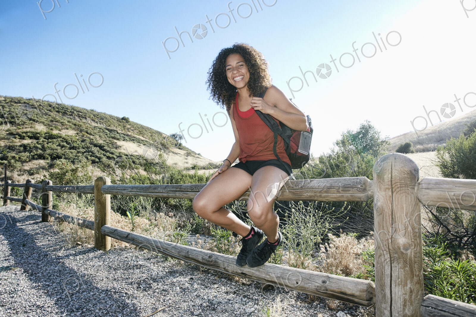 Young woman with curly brown hair hiking in urban park.