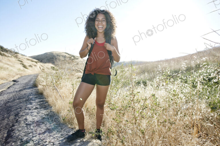Young woman with curly brown hair hiking in urban park.