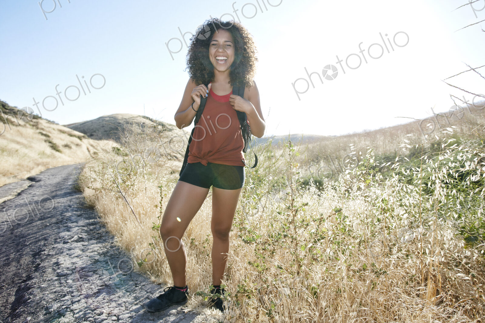 Young woman with curly brown hair hiking in urban park.