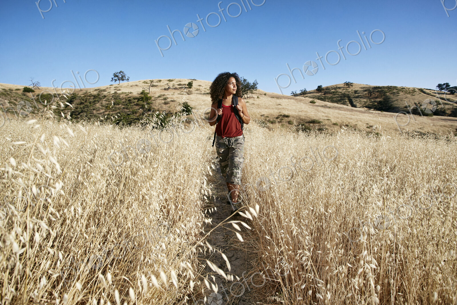 Young woman with curly brown hair hiking in urban park.