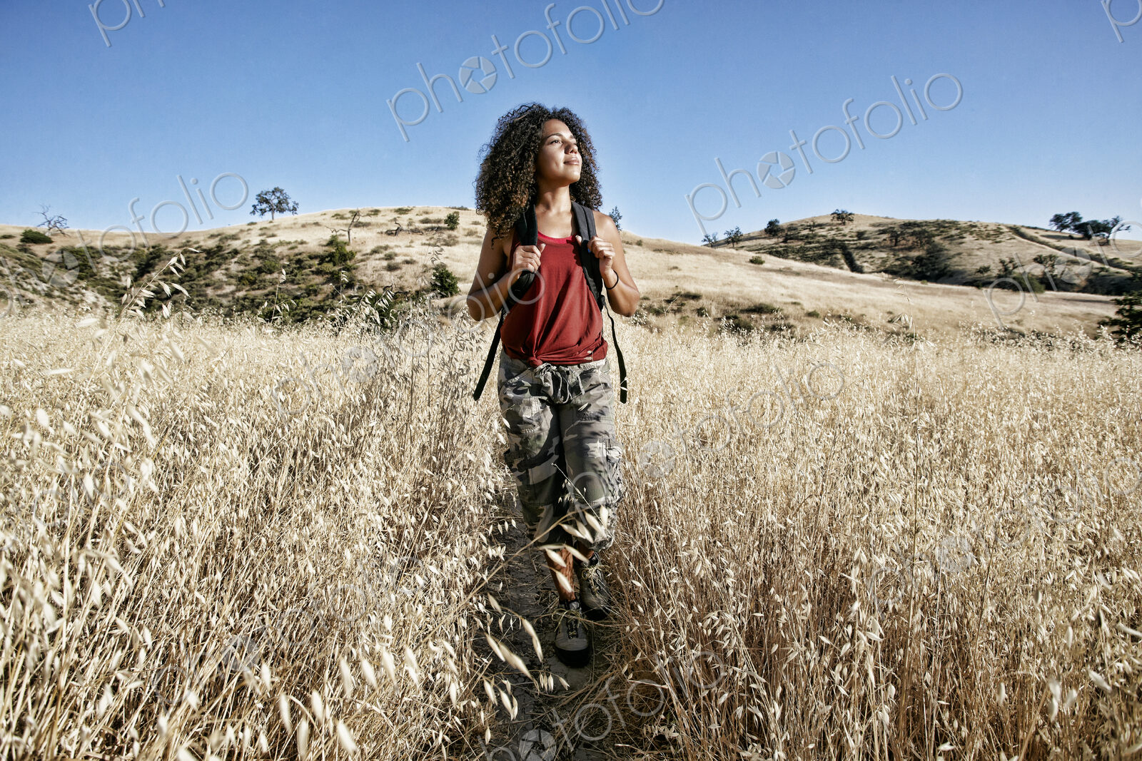Young woman with curly brown hair hiking in urban park.