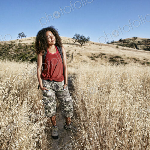 Young woman with curly brown hair hiking in urban park. Young woman with curly brown hair hiking in urban park.