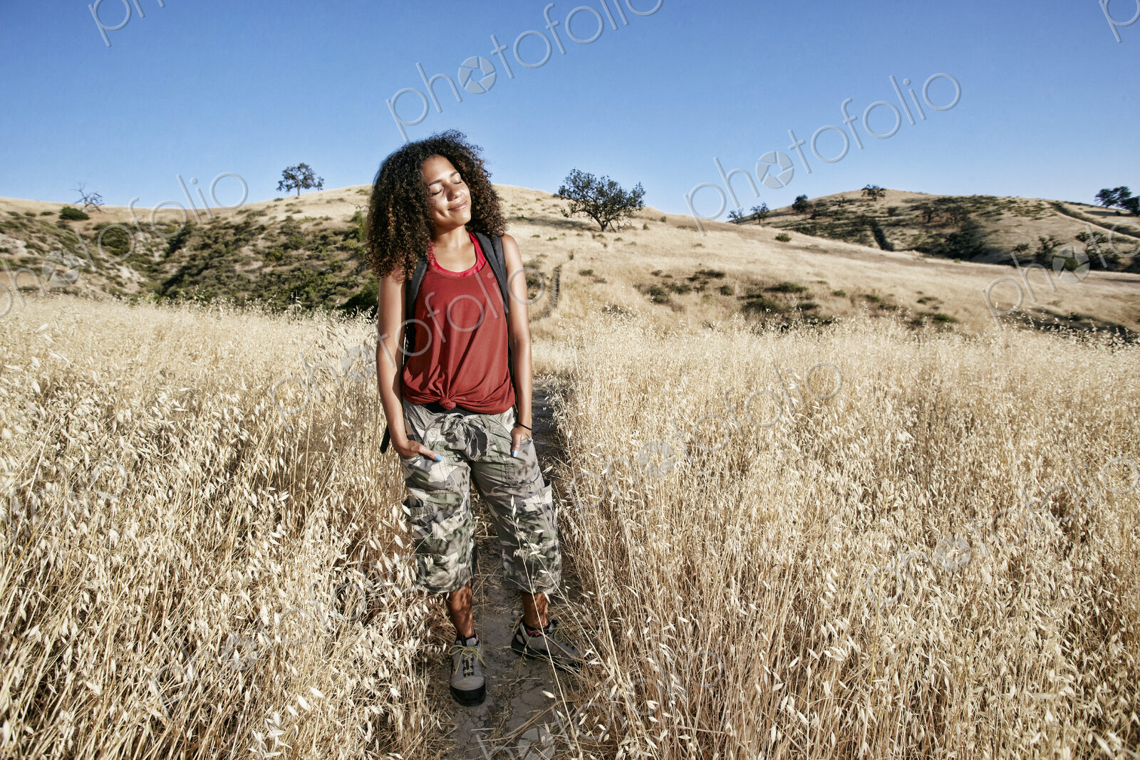 Young woman with curly brown hair hiking in urban park.