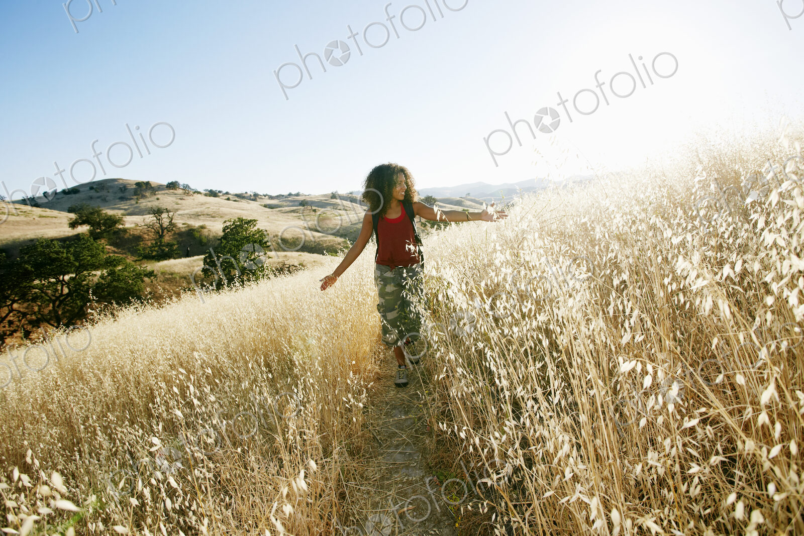 Young woman with curly brown hair hiking in urban park.