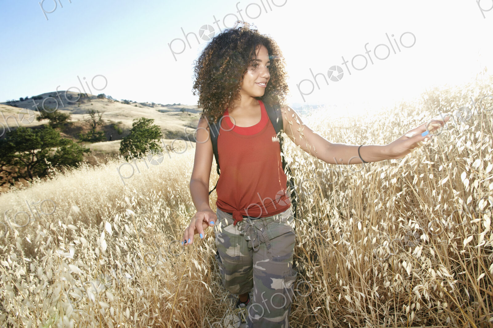 Young woman with curly brown hair hiking in urban park.