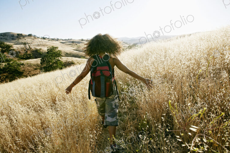 Young woman with curly brown hair hiking in urban park.