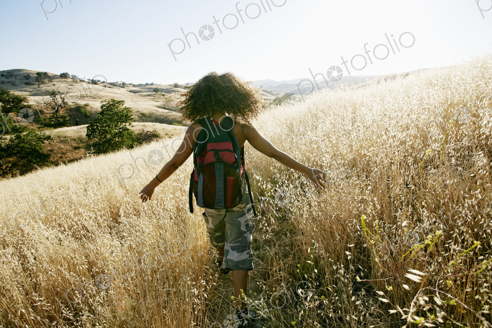 Young woman with curly brown hair hiking in urban park.