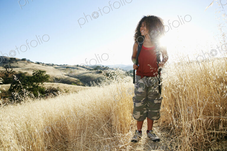 Young woman with curly brown hair hiking in urban park.