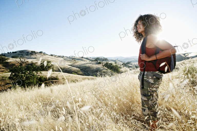 Young woman with curly brown hair hiking in urban park.