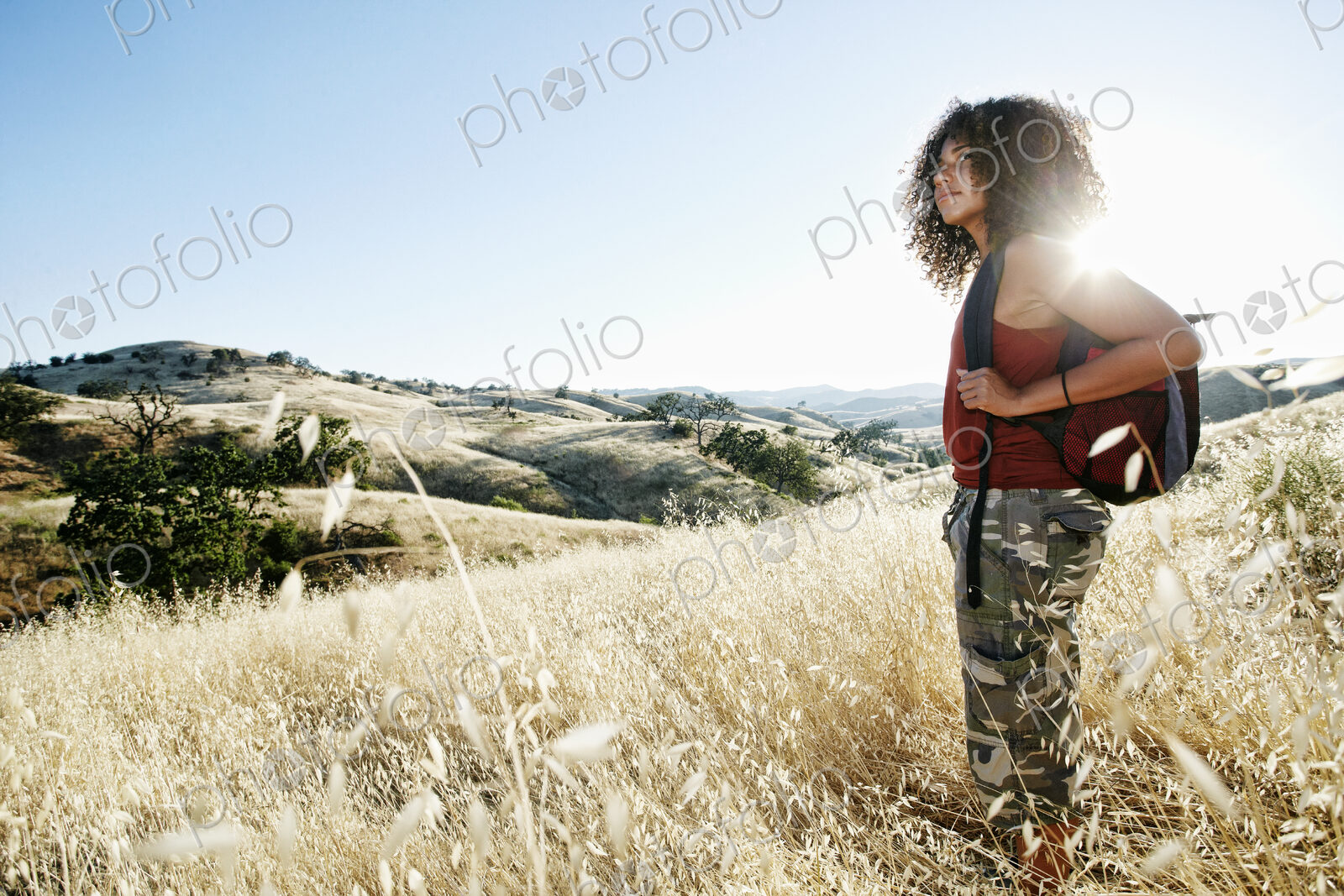 Young woman with curly brown hair hiking in urban park.