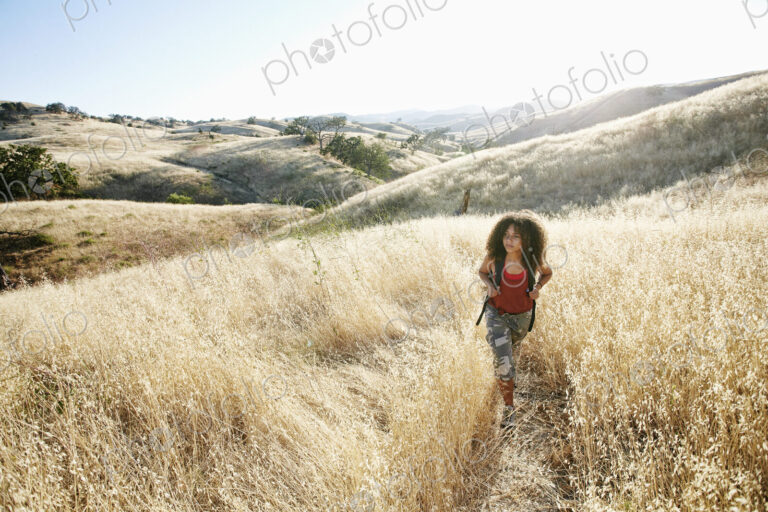 Young woman with curly brown hair hiking in urban park.