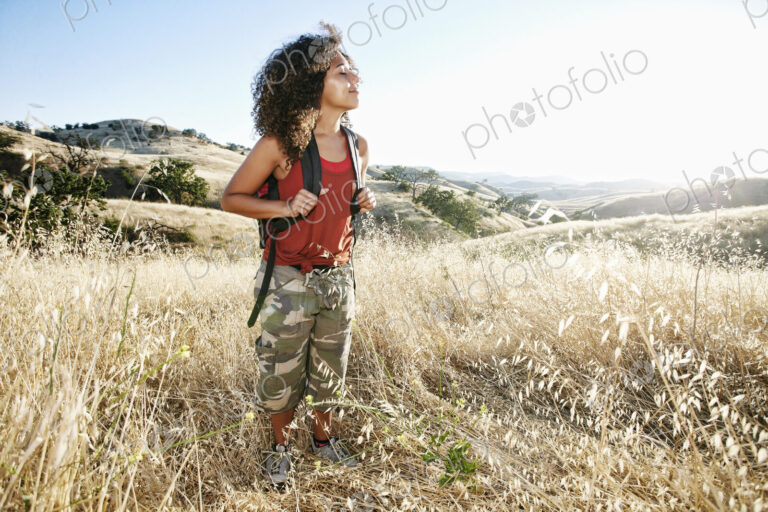 Young woman with curly brown hair hiking in urban park.