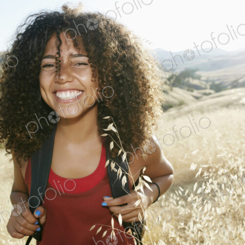 Young woman with curly brown hair hiking in urban park, smiling at camera. Young woman with curly brown hair hiking in urban park, smiling at camera.