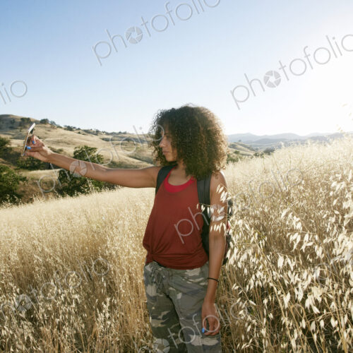 Young woman with curly brown hair hiking in urban park, taking picture with mobile phone. Young woman with curly brown hair hiking in urban park, taking picture with mobile phone.