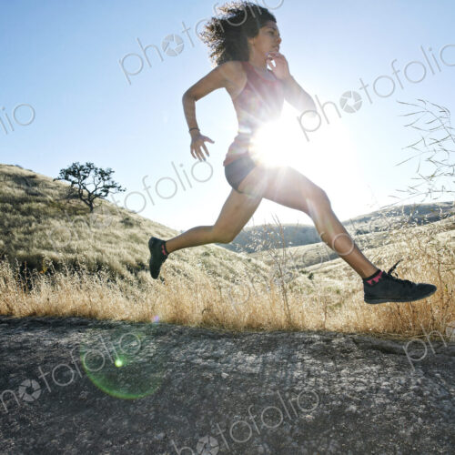 Young woman with curly brown hair running in urban park. Young woman with curly brown hair running in urban park.