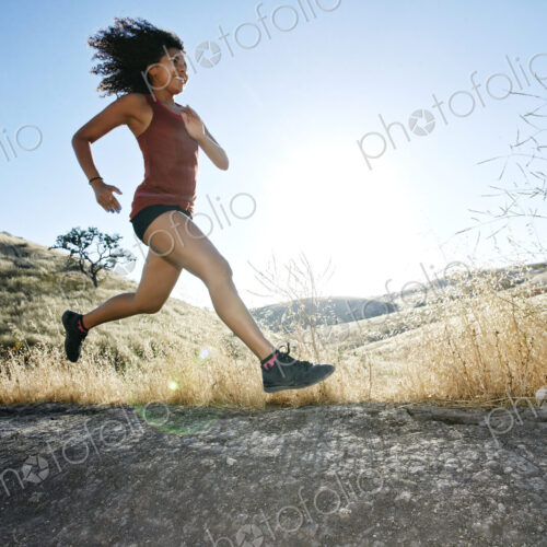 Young woman with curly brown hair running in urban park. Young woman with curly brown hair running in urban park.