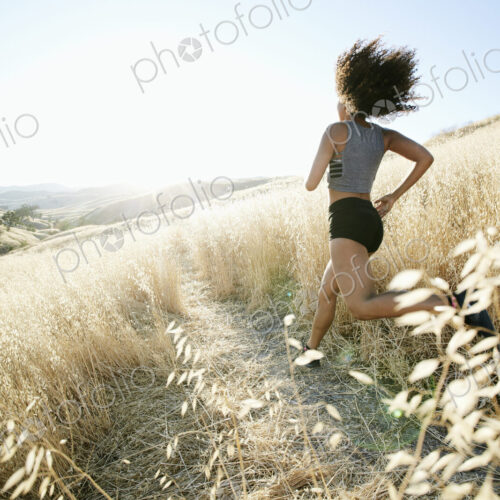 Young woman with curly brown hair running in urban park. Young woman with curly brown hair running in urban park.