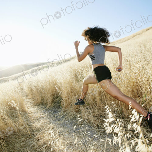 Young woman with curly brown hair running in urban park. Young woman with curly brown hair running in urban park.