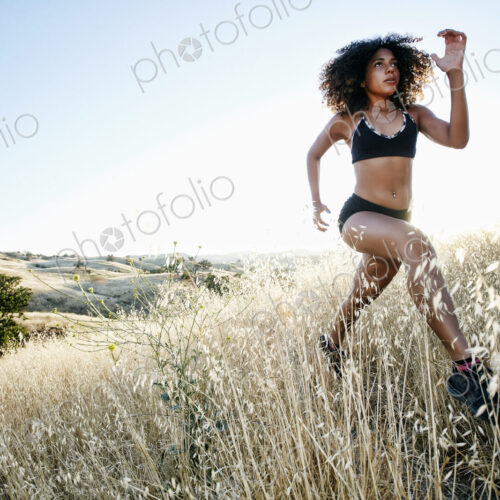 Young woman with curly brown hair running in urban park. Young woman with curly brown hair running in urban park.