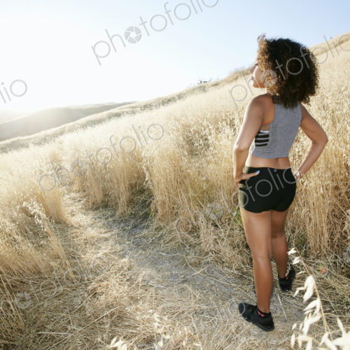 Young woman with curly brown hair standing on path in urban park. Young woman with curly brown hair standing on path in urban park.