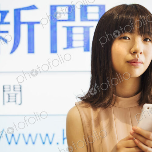 Young woman with long brown hair holding a mobile phone.