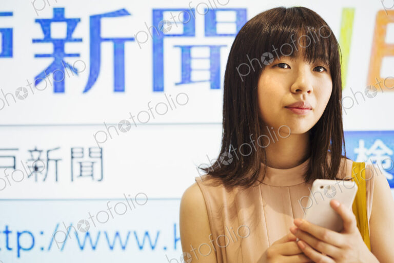 Young woman with long brown hair holding a mobile phone.