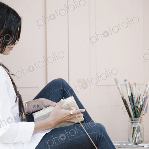Young woman with long brown hair, holding a sketch book and paint brush. Young woman with long brown hair, holding a sketch book and paint brush.