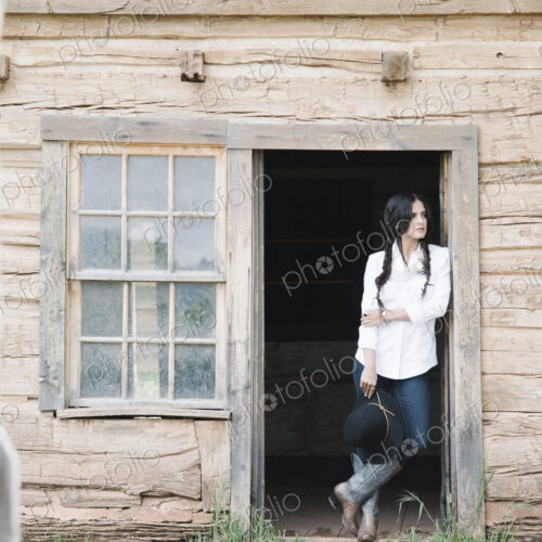 Young woman with long brown hair in braids, standing in the doorway of a wooden cabin. Young woman with long brown hair in braids, standing in the doorway of a wooden cabin.