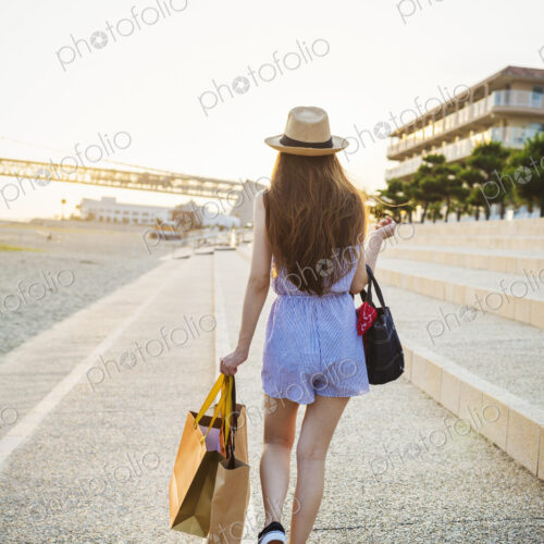 Young woman with long brown hair, wearing Panama hat and carrying shopping bags. Young woman with long brown hair, wearing Panama hat and carrying shopping bags.