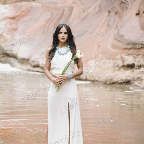 Young woman with long brown hair, wearing a long white dress, standing by a river,… Young woman with long brown hair, wearing a long white dress, standing by a river,…