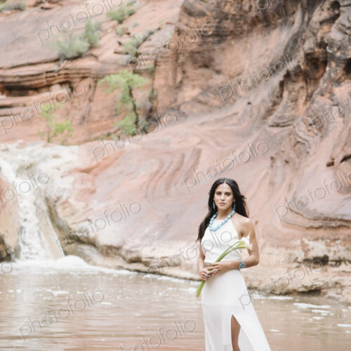 Young woman with long brown hair, wearing a long white dress, standing by a river,… Young woman with long brown hair, wearing a long white dress, standing by a river,…
