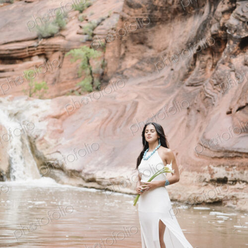 Young woman with long brown hair, wearing a long white dress, standing by a river,… Young woman with long brown hair, wearing a long white dress, standing by a river,…