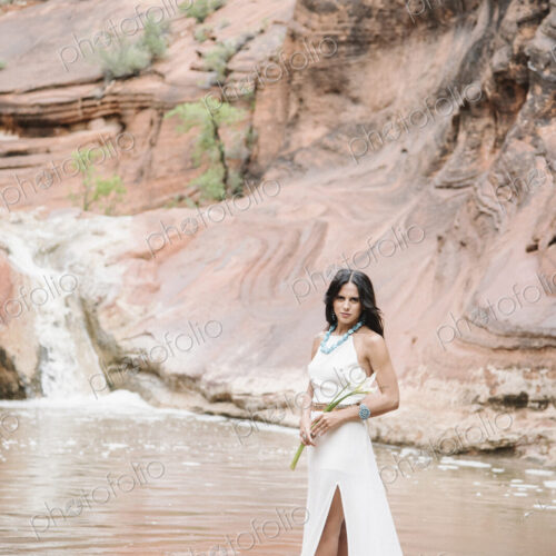 Young woman with long brown hair, wearing a long white dress, standing by a river,… Young woman with long brown hair, wearing a long white dress, standing by a river,…