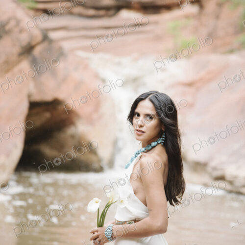 Young woman with long brown hair, wearing a long white dress, standing by a river,… Young woman with long brown hair, wearing a long white dress, standing by a river,…