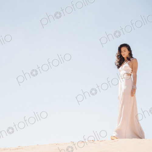 Young woman with long brown hair, wearing a long white dress, standing in a desert. Young woman with long brown hair, wearing a long white dress, standing in a desert.