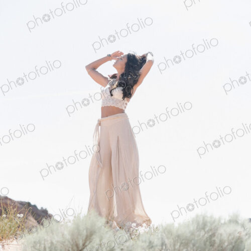 Young woman with long brown hair, wearing a long white dress, standing in the prairie. Young woman with long brown hair, wearing a long white dress, standing in the prairie.