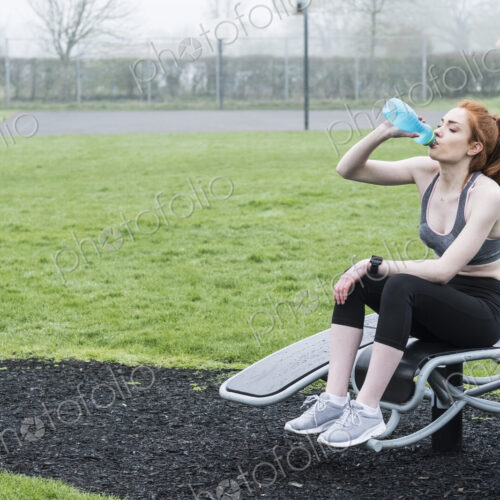 Young woman with long red hair wearing sportswear, exercising outdoors. Young woman with long red hair wearing sportswear, exercising outdoors.