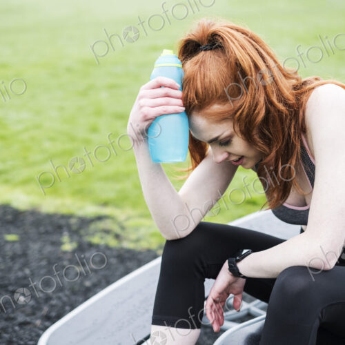 Young woman with long red hair wearing sportswear, exercising outdoors. Young woman with long red hair wearing sportswear, exercising outdoors.