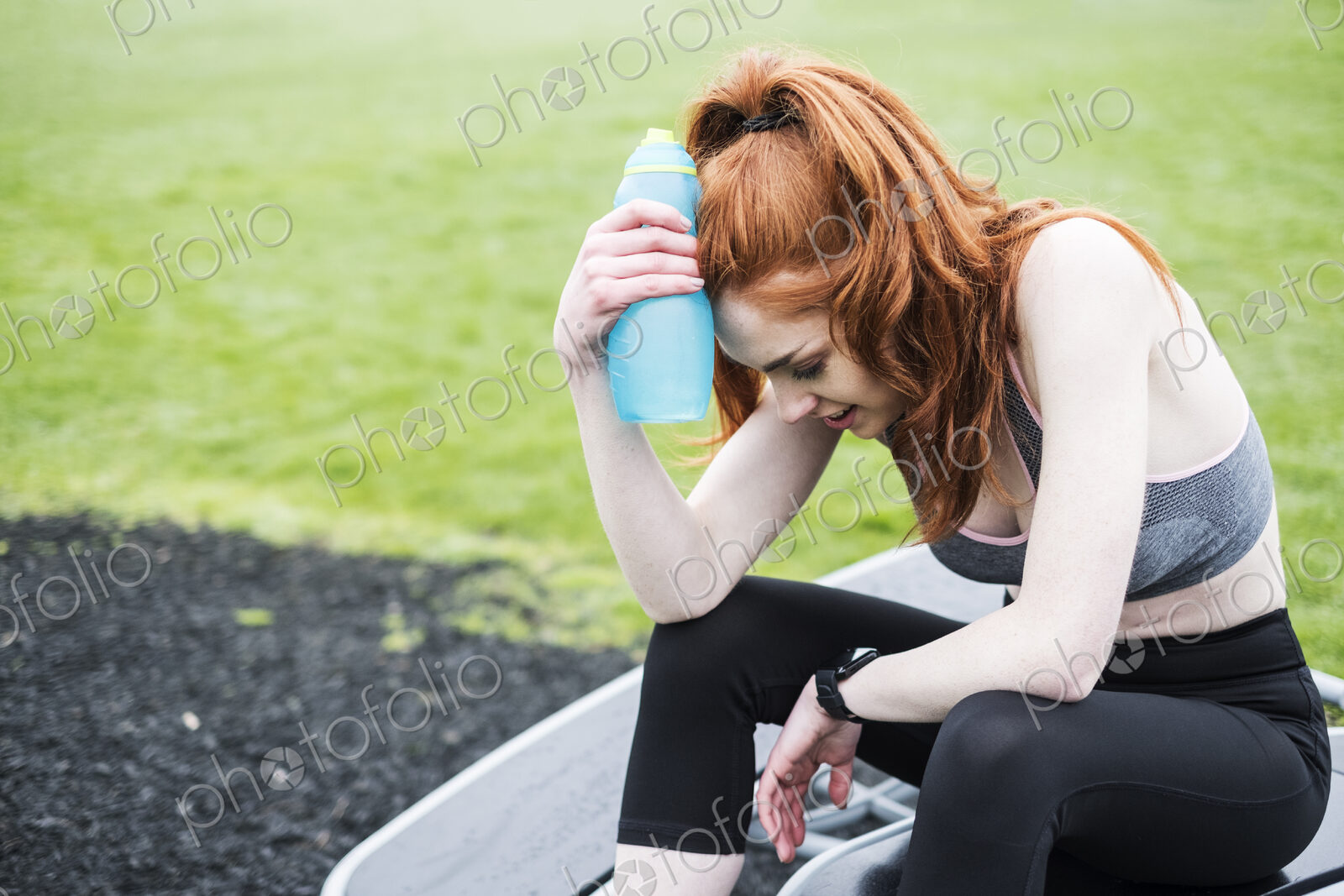 Young woman with long red hair wearing sportswear, exercising outdoors.