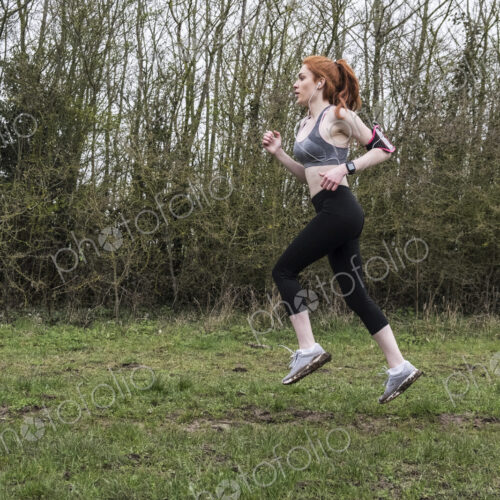 Young woman with long red hair wearing sportswear, exercising outdoors. Young woman with long red hair wearing sportswear, exercising outdoors.