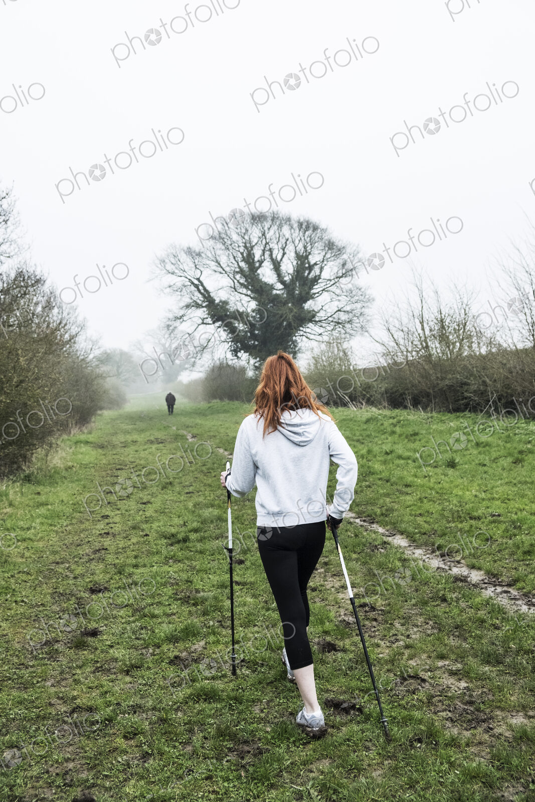 Young woman with long red hair wearing sportswear, exercising outdoors.
