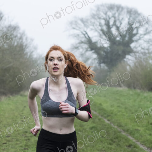 Young woman with long red hair wearing sportswear, exercising outdoors, looking at camera. Young woman with long red hair wearing sportswear, exercising outdoors, looking at camera.